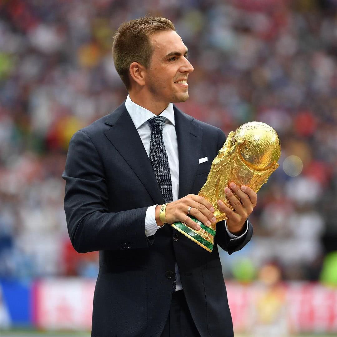 De terno, Philipp Lahm segura o troféu da Copa do Mundo