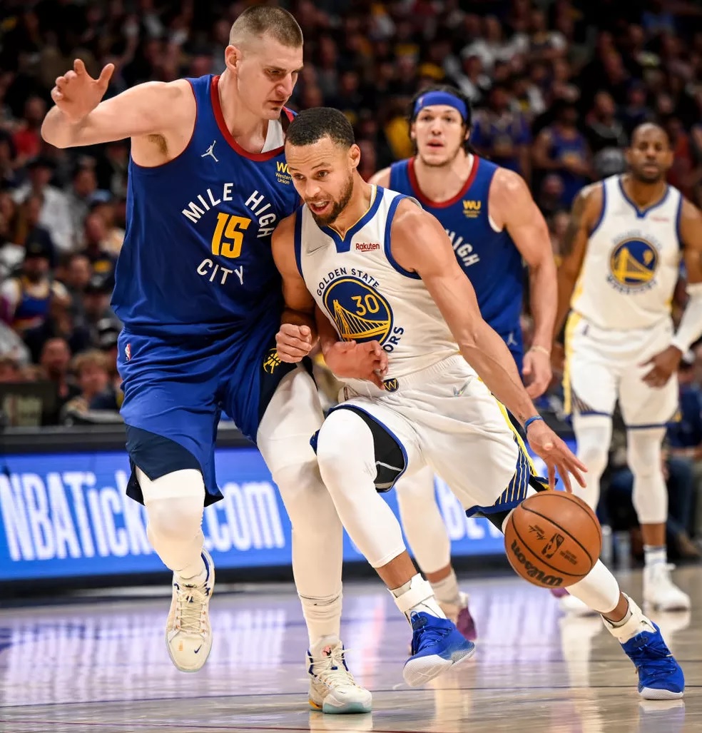 Estrelas de Golden State Warriors e Nuggets, Stephen Curry e Nikola Jokic, duelando em quadra pela NBA