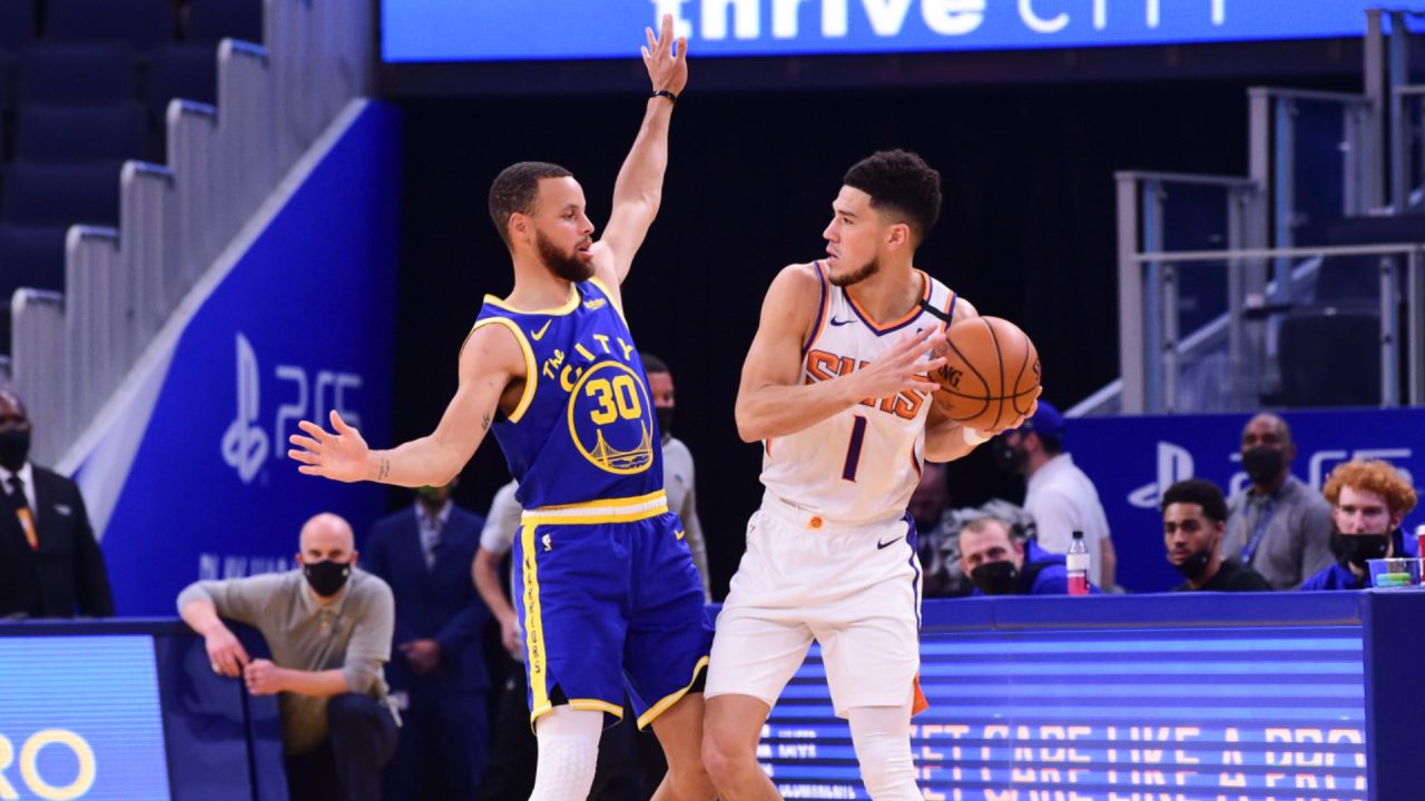 Estrelas de Suns e Warriors, Booker e Curry, duelando em quadra pela NBA